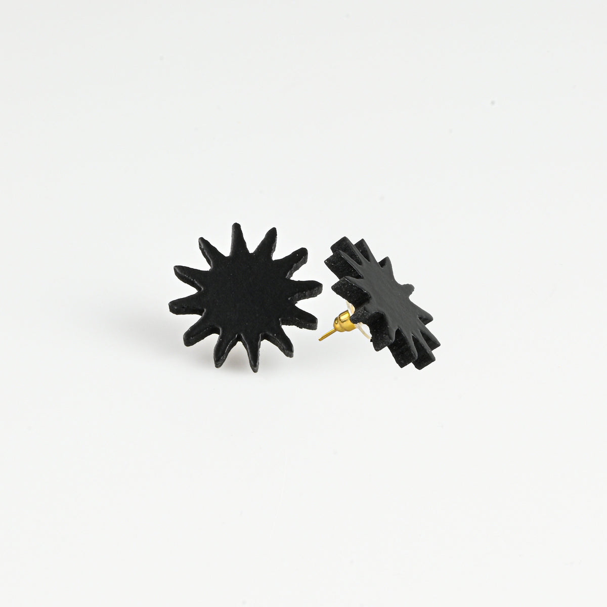 A pair of black starburst stud earrings with gold-tone posts, shown on a clean white background.