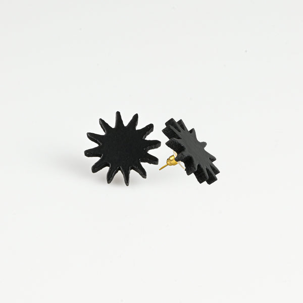 A pair of black starburst stud earrings with gold-tone posts, shown on a clean white background.