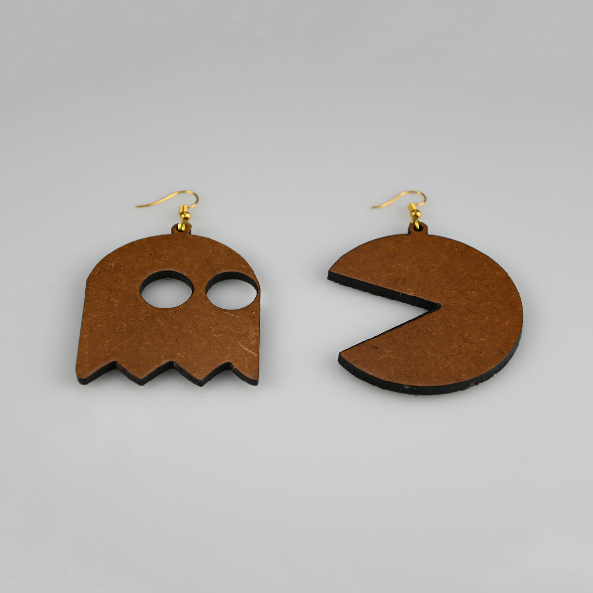 A pair of wooden dangle earrings shaped like a ghost and a Pac-Man style mouth, shown on a plain light gray background.
